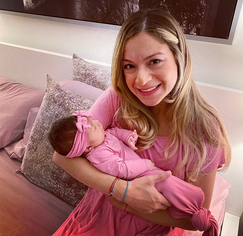 Mom in the Three Little Tots labor and delivery gown holding her newborn baby girl in the Three Little Tots Knotted Baby Gown