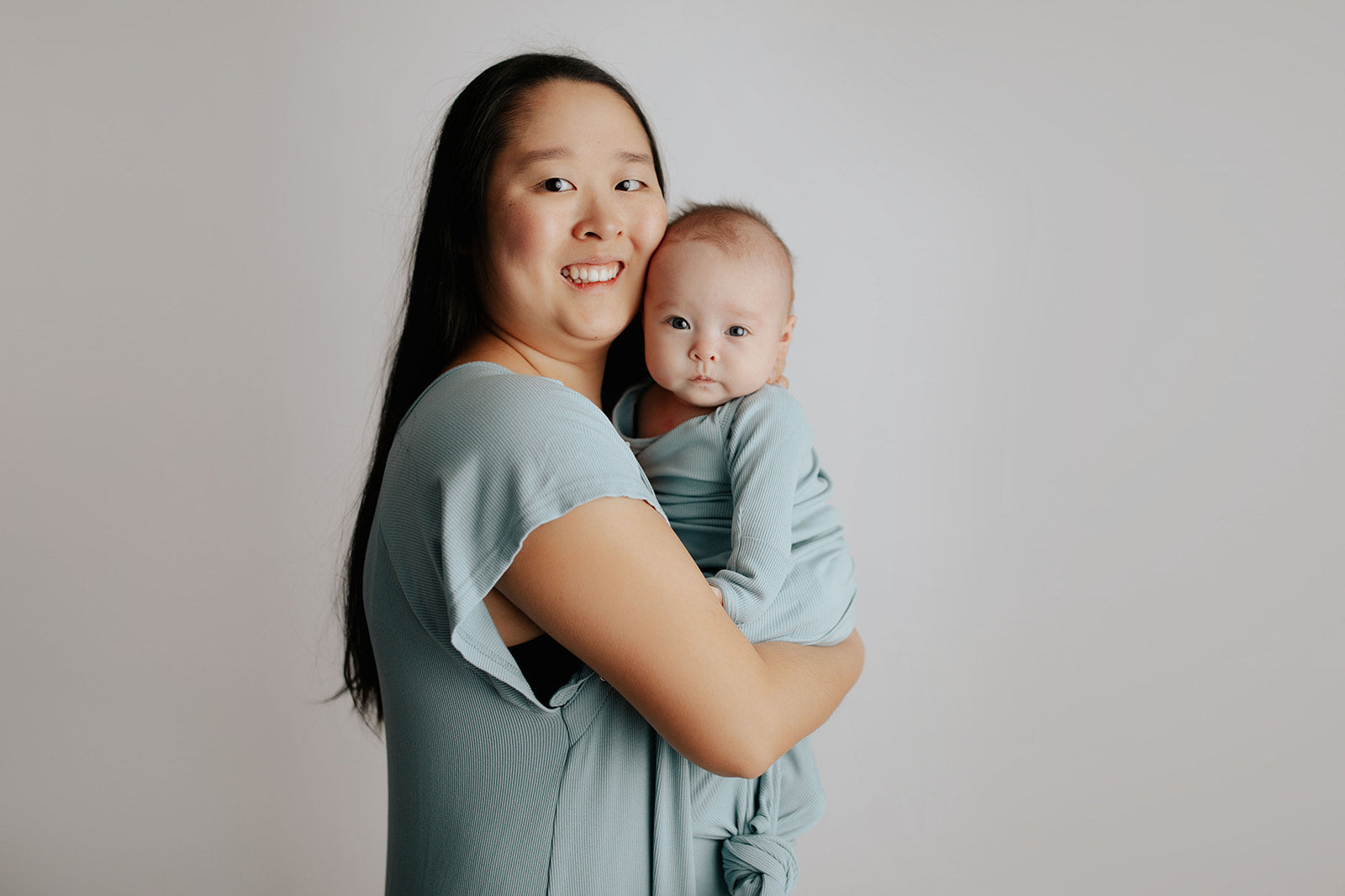 breastfeeding newborn in Three Little Tots matching blue bird labor gown and blue bird knotted baby gown