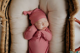 Luxuriously soft modal knotted baby gowns for newborn babies, offering comfort, easy diaper changes, and style. Three Little Tots Rose Pink Knotted baby gown. Knotted tie bottom mimics the womb to bring comfort to your newborn. Newborn baby in Snuggle Me organics in a Plum + Sparrow Moses Basket