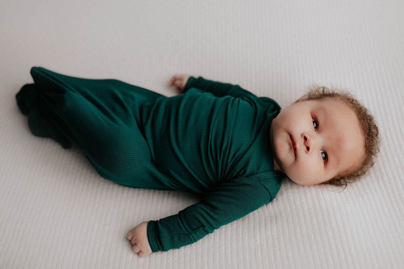Newborn family photoshoot. Baby is wearing Three Little Tots Forest Green Knotted Gown