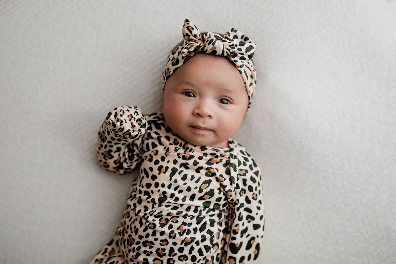 A newborn photoshoot idea with the Leopard Three Little Tots knotted baby gown with a cute bow. Showcasing the fold over mittens.