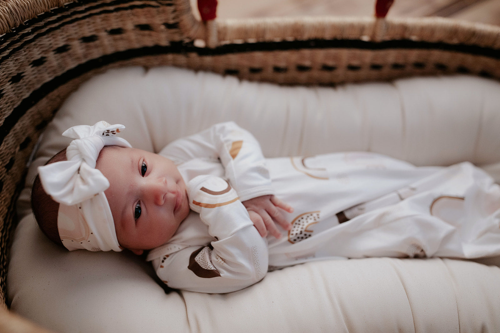 Luxuriously soft modal knotted baby gowns for rainbow babies, offering comfort, easy diaper changes, and style. Three Little Tots Rainbow Knotted Baby gown in a Plum + Sparrow Moses Basket