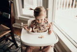 Toddler eating bananas staying clean with the Three Little Tots Floral Silicone Bib 
