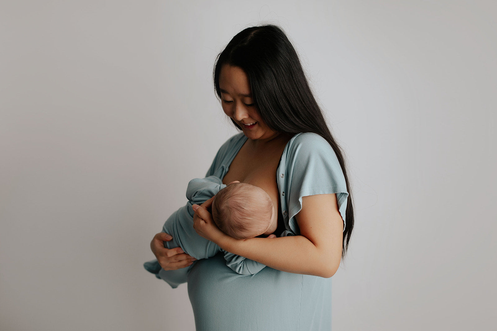 breastfeeding newborn in Three Little Tots matching blue bird labor gown and blue bird knotted baby gown