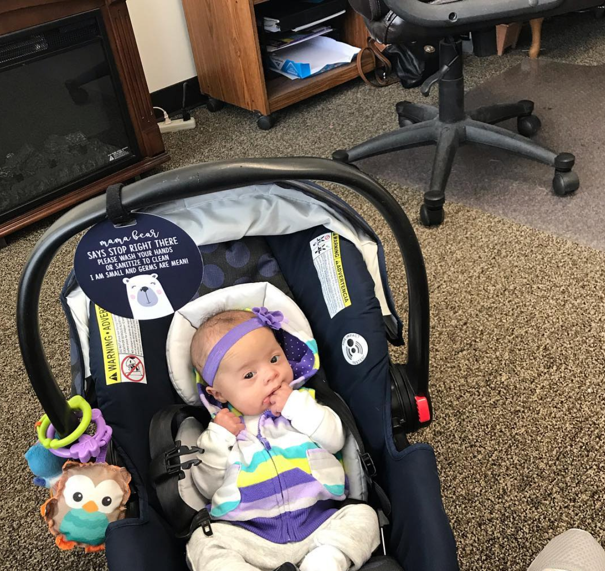 Newborn baby with a Three Little Tots Car Seat Sign on an infant car seat sign