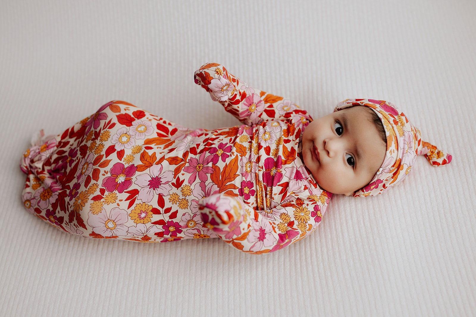 A cute newborn photoshoot featuring the Wild Child Three Little Tots knotted Baby Gown