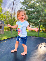 Little girl jumping on the trampoline wearing a Three Little Tots lavender silicone beaded pacifier clips