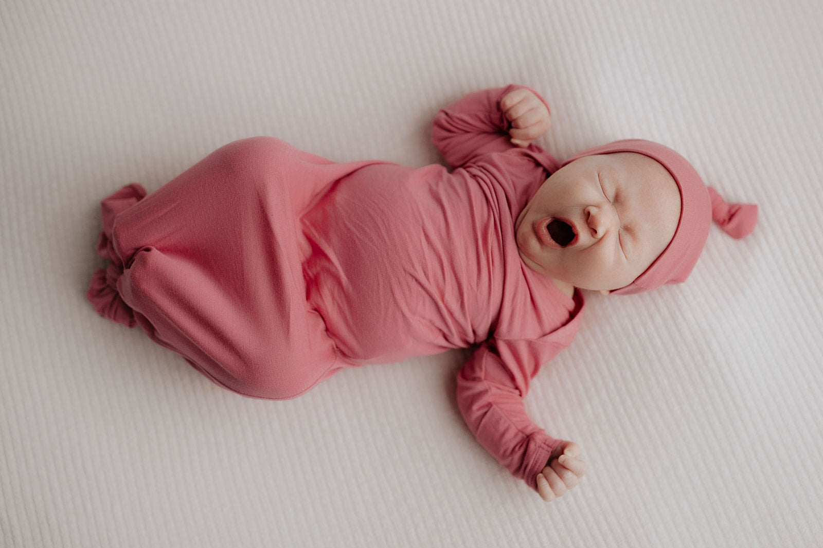 a photo of a newborn baby girl yawning in the Tree Little Tots Knotted Baby Gown