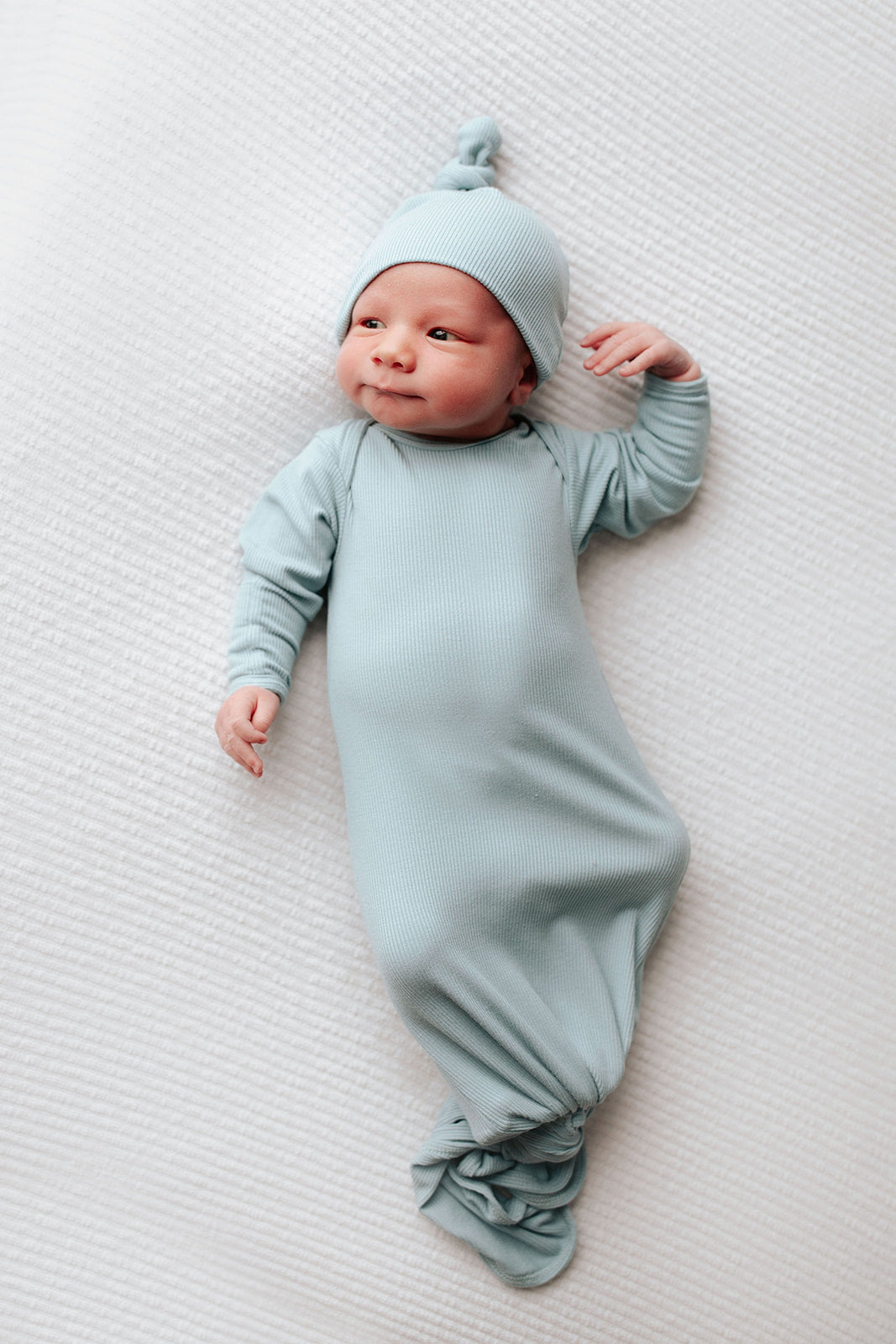 newborn baby with open eyes photoshoot with a knotted baby gown