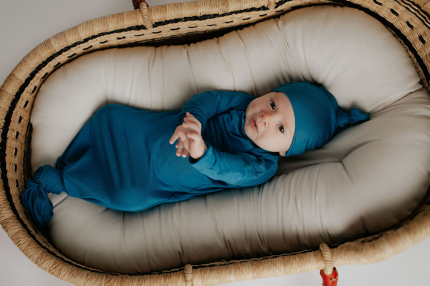 plum + sparrow baby Moses basket with newborn baby in a knotted gown