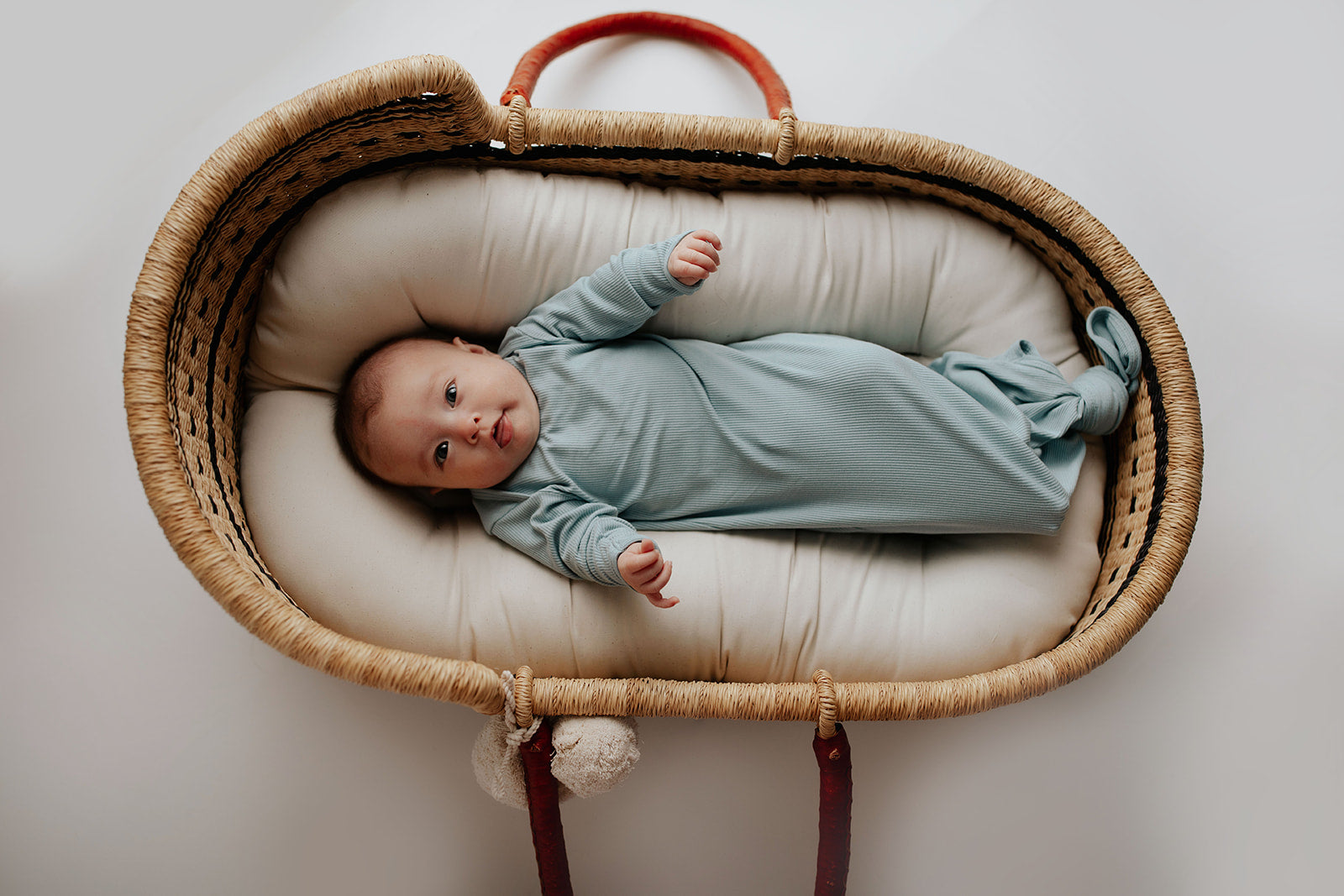 Newborn photoshoot with a Plum + Sparrow Moses basket and a Three Little Tots newborn knotted baby gown