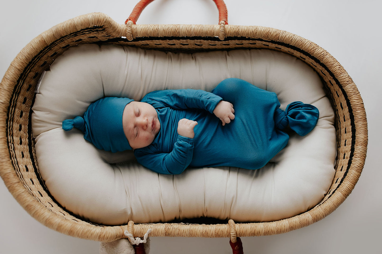 plum + sparrow baby Moses basket with newborn baby in a knotted gown