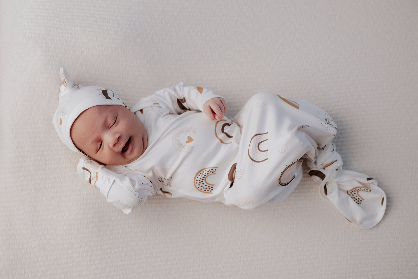 Newborn photoshoot idea for a rainbow  baby gown with the Three Little Tots rainbow knotted baby gown