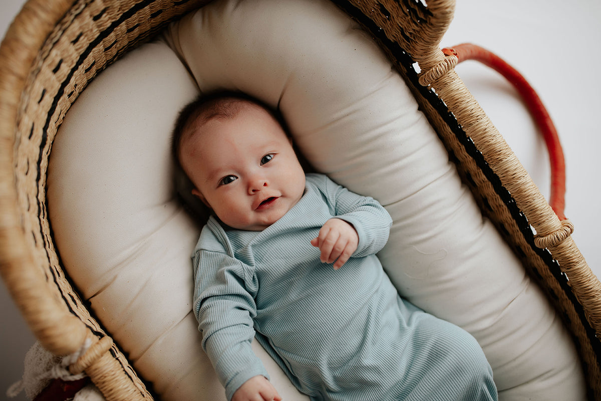Newborn photoshoot with a Plum + Sparrow Moses basket and a Three Little Tots newborn knotted baby gown